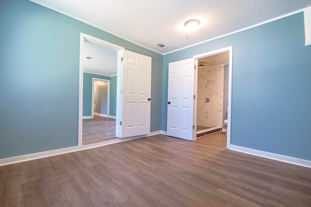 interior space with a textured ceiling, hardwood / wood-style flooring, and connected bathroom