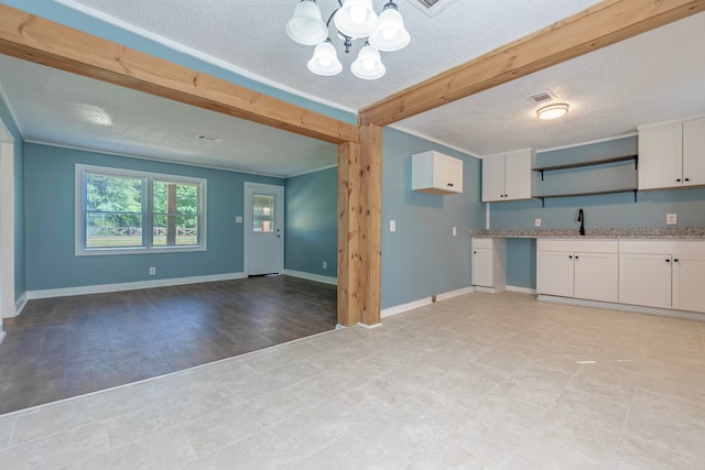 kitchen featuring white cabinets, light wood-type flooring, a chandelier, sink, and a textured ceiling