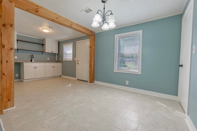 kitchen with light tile patterned floors, decorative light fixtures, a notable chandelier, sink, and a textured ceiling