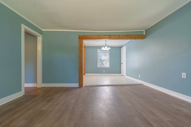 spare room featuring dark wood-type flooring, a textured ceiling, and an inviting chandelier