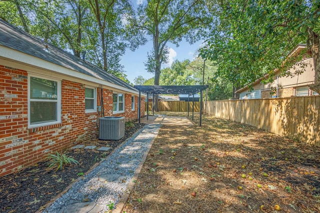 view of yard with central AC unit and a pergola