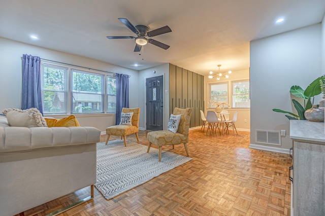 living room with ceiling fan with notable chandelier, plenty of natural light, and light parquet floors