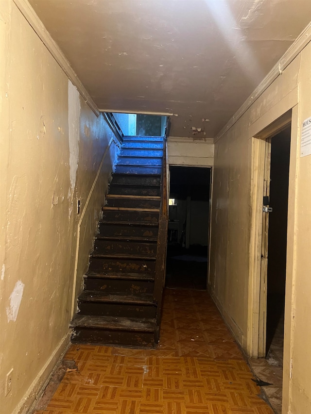 staircase with parquet floors and crown molding