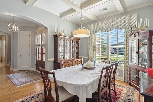 dining area with coffered ceiling, light hardwood / wood-style floors, beamed ceiling, and ornamental molding