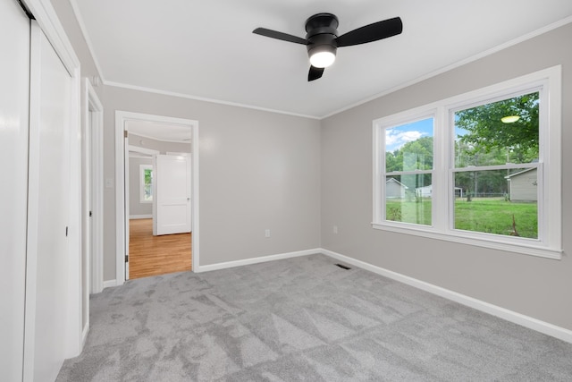 unfurnished bedroom featuring crown molding, ceiling fan, light carpet, and multiple windows