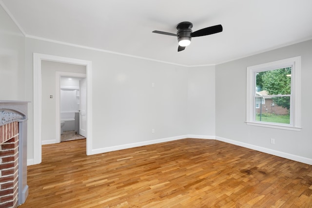 spare room featuring a fireplace, ornamental molding, ceiling fan, and light hardwood / wood-style floors