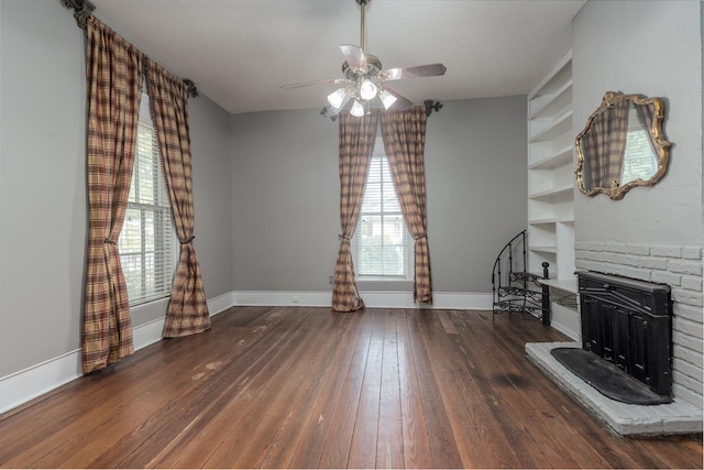 living room with ceiling fan, a fireplace, dark hardwood / wood-style floors, and a textured ceiling