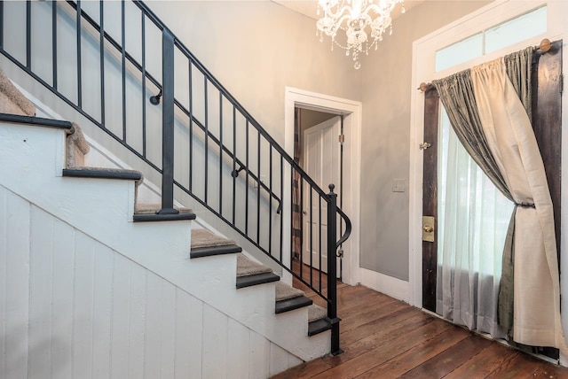 stairs featuring hardwood / wood-style floors and an inviting chandelier