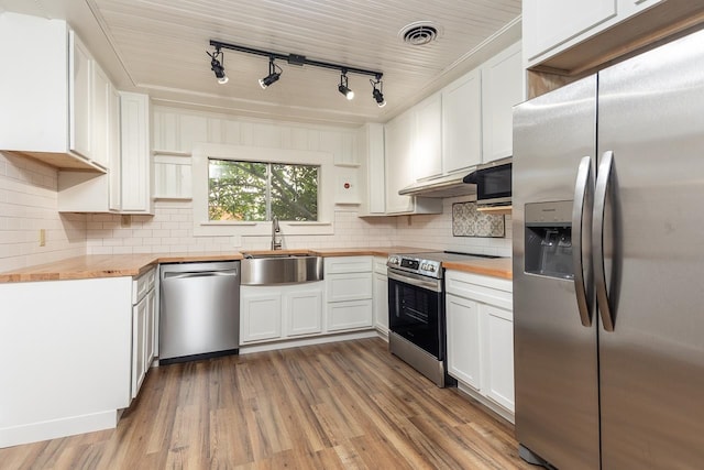 kitchen with appliances with stainless steel finishes, white cabinetry, hardwood / wood-style flooring, and wood counters