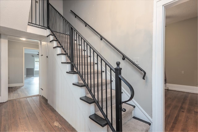 stairway featuring a textured ceiling and hardwood / wood-style flooring