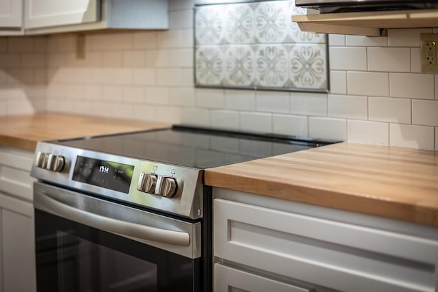 kitchen featuring white cabinets, tasteful backsplash, butcher block counters, and electric stove