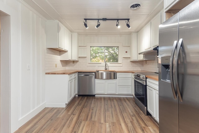 kitchen with butcher block countertops, hardwood / wood-style floors, stainless steel appliances, and white cabinets