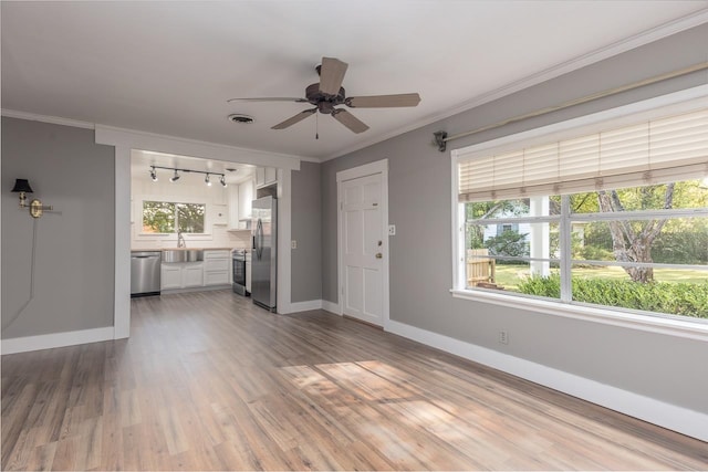 unfurnished living room featuring dark hardwood / wood-style flooring, crown molding, sink, ceiling fan, and track lighting