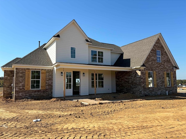 traditional-style home with brick siding, a porch, and a shingled roof