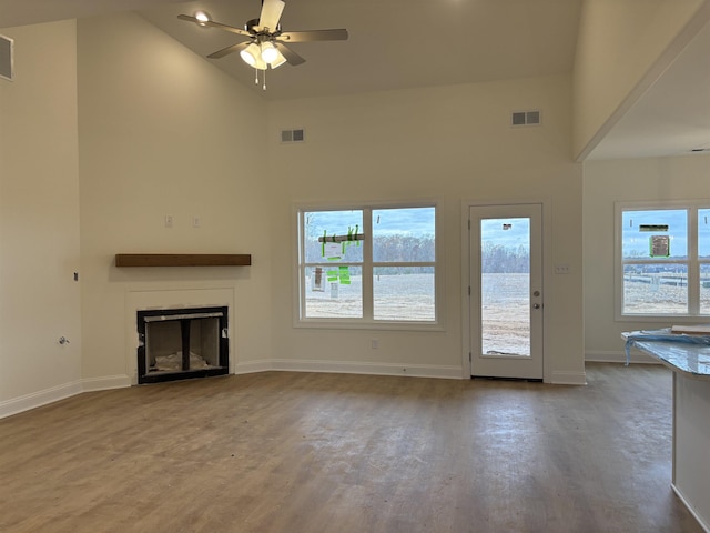 unfurnished living room with ceiling fan, hardwood / wood-style floors, and high vaulted ceiling