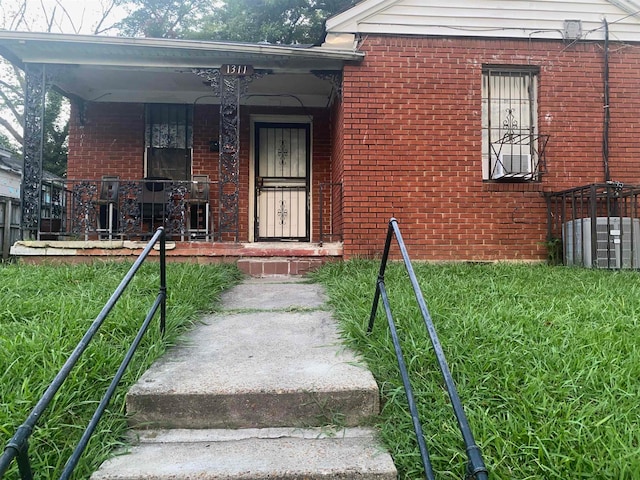 view of exterior entry with brick siding and a porch