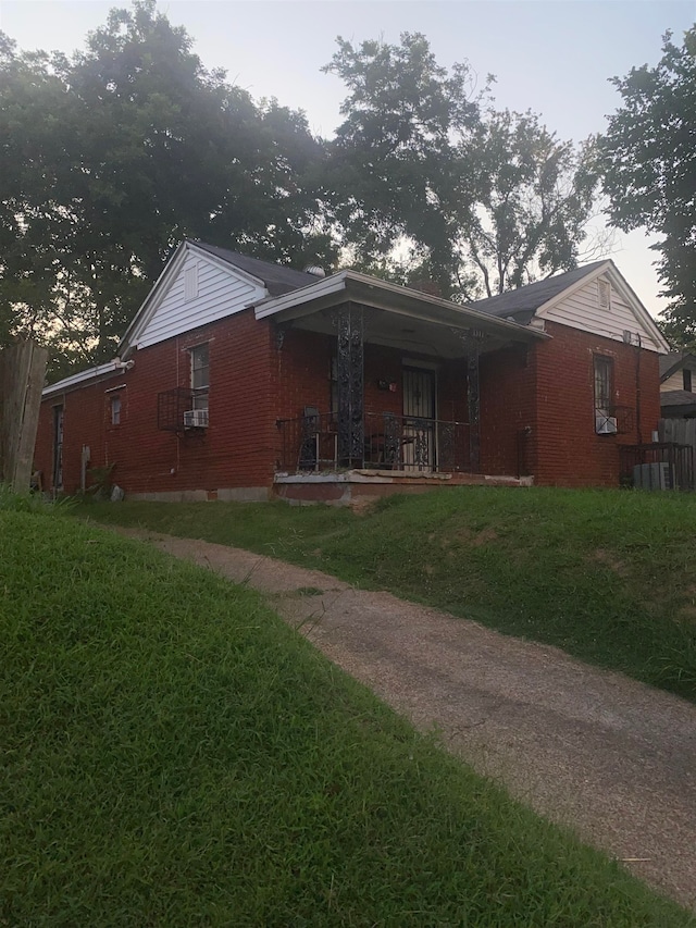 view of front facade featuring covered porch, a front yard, crawl space, and brick siding