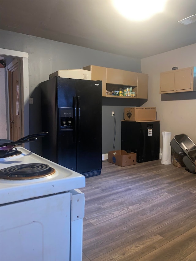 kitchen with wood finished floors, electric range, cream cabinets, and black fridge