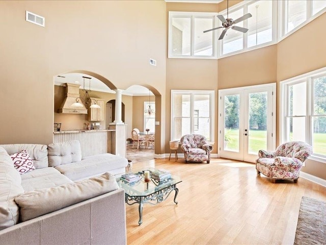 living room featuring ceiling fan, hardwood / wood-style floors, french doors, and a high ceiling