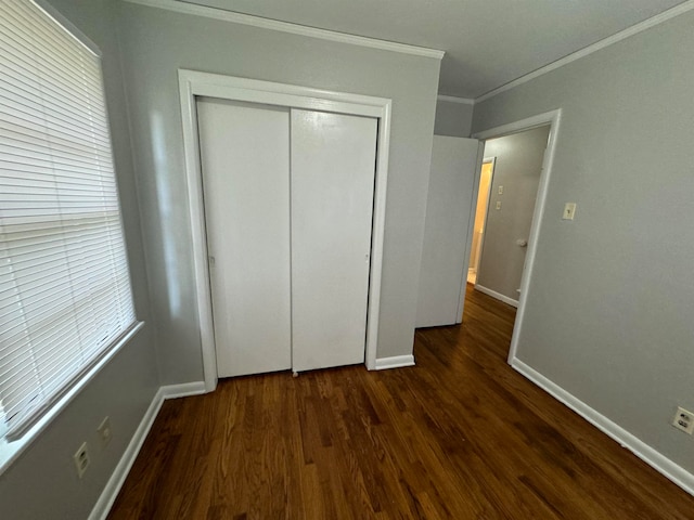 unfurnished bedroom featuring a closet, multiple windows, dark hardwood / wood-style flooring, and ornamental molding