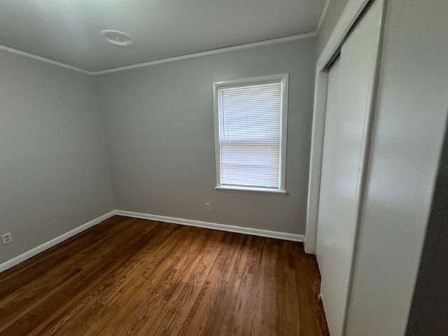 empty room with dark hardwood / wood-style flooring and ornamental molding