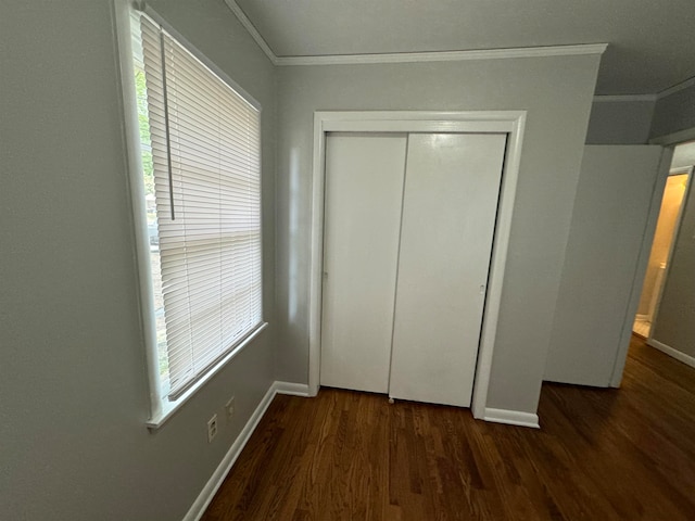 unfurnished bedroom with crown molding, multiple windows, dark wood-type flooring, and a closet