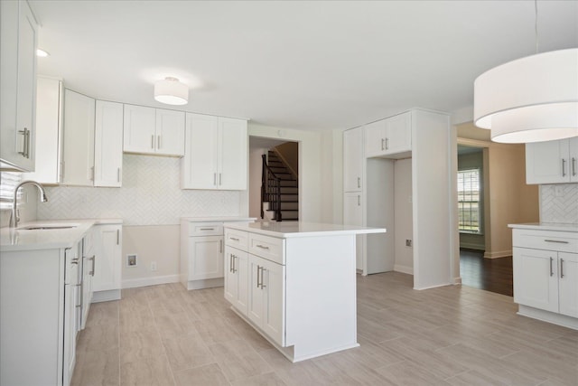 kitchen with a center island, light hardwood / wood-style floors, white cabinetry, and sink