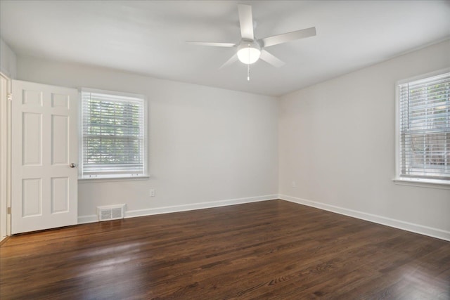 spare room featuring ceiling fan, dark hardwood / wood-style flooring, and a healthy amount of sunlight