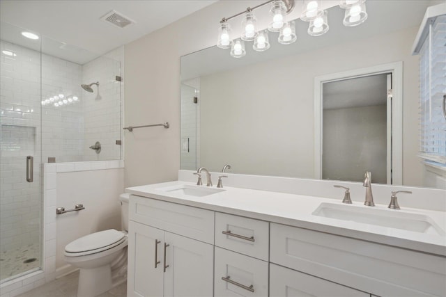 bathroom with a shower with shower door, toilet, and vanity