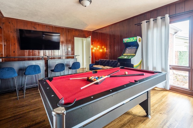 game room featuring a textured ceiling, pool table, wood-type flooring, crown molding, and wooden walls