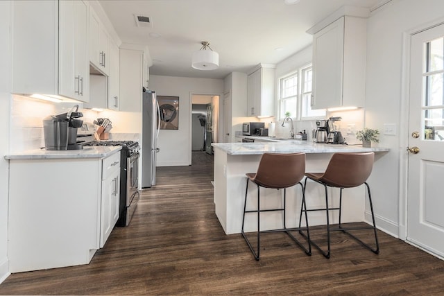 kitchen featuring white cabinets, appliances with stainless steel finishes, dark hardwood / wood-style floors, and a healthy amount of sunlight