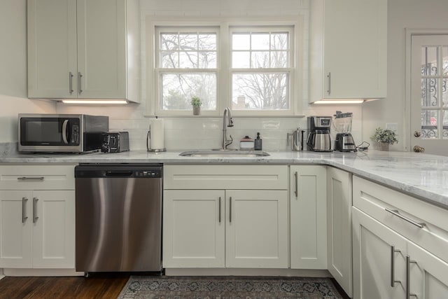 kitchen with white cabinetry, stainless steel appliances, dark hardwood / wood-style flooring, light stone counters, and sink