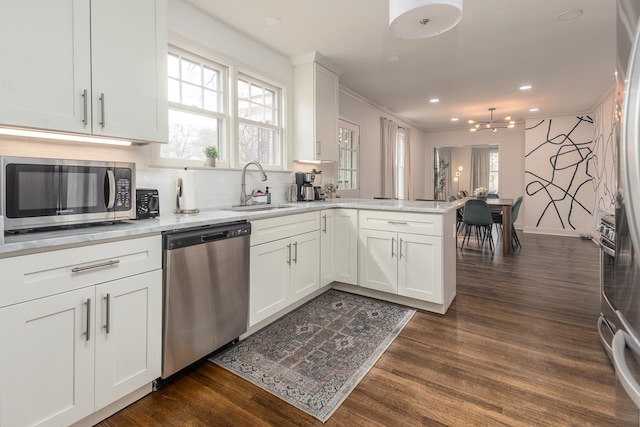 kitchen with stainless steel appliances, kitchen peninsula, sink, dark hardwood / wood-style floors, and white cabinets