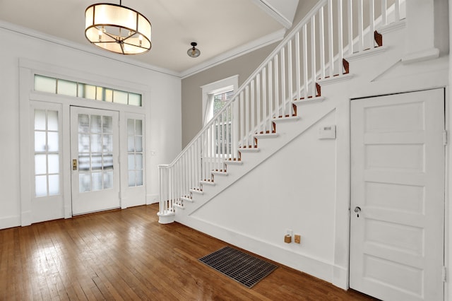 foyer featuring crown molding, an inviting chandelier, and hardwood / wood-style flooring