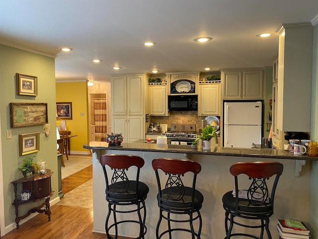 kitchen featuring white fridge, high end range, light hardwood / wood-style floors, and crown molding