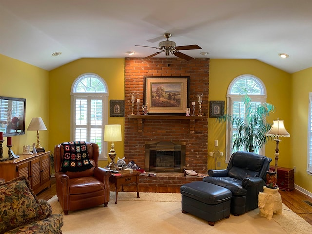 living room featuring hardwood / wood-style floors, ceiling fan, a fireplace, and vaulted ceiling