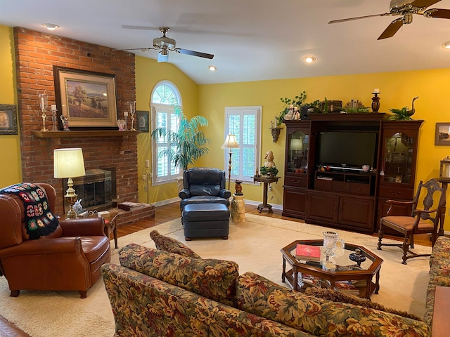 living room featuring a fireplace, light wood-type flooring, lofted ceiling, and ceiling fan