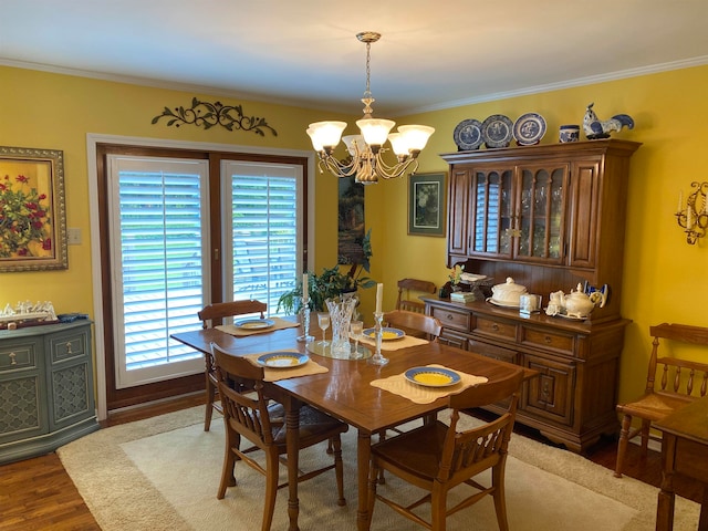 dining area with ornamental molding, a chandelier, and hardwood / wood-style floors