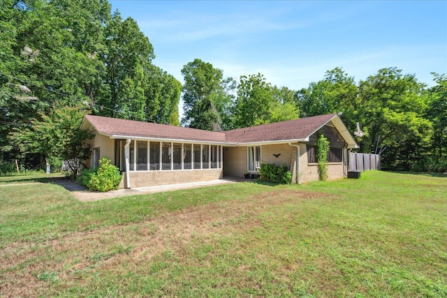 rear view of house with a yard and a sunroom