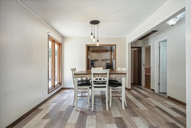 dining area featuring crown molding, a textured ceiling, and light hardwood / wood-style flooring