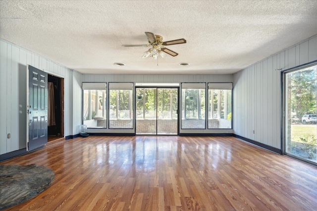 unfurnished room with a textured ceiling, plenty of natural light, ceiling fan, and hardwood / wood-style flooring