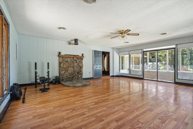 exercise room featuring ceiling fan, hardwood / wood-style flooring, and a textured ceiling