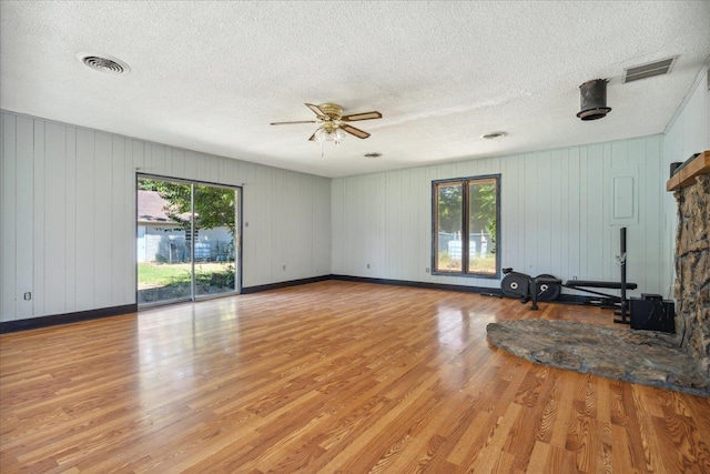 unfurnished living room with light wood-type flooring, ceiling fan, and a textured ceiling