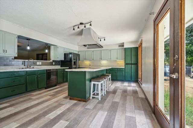 kitchen featuring green cabinets, a center island, light hardwood / wood-style flooring, black appliances, and a breakfast bar