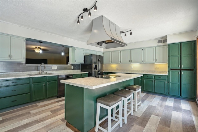 kitchen featuring a textured ceiling, light hardwood / wood-style flooring, a kitchen bar, black appliances, and a center island