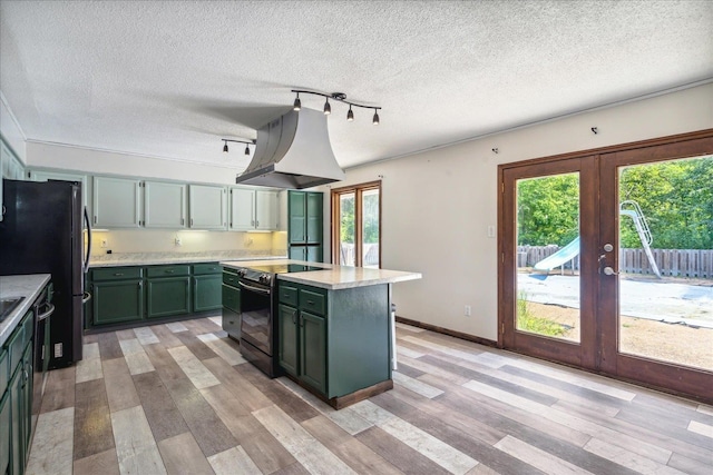 kitchen featuring black appliances, light hardwood / wood-style flooring, premium range hood, and french doors