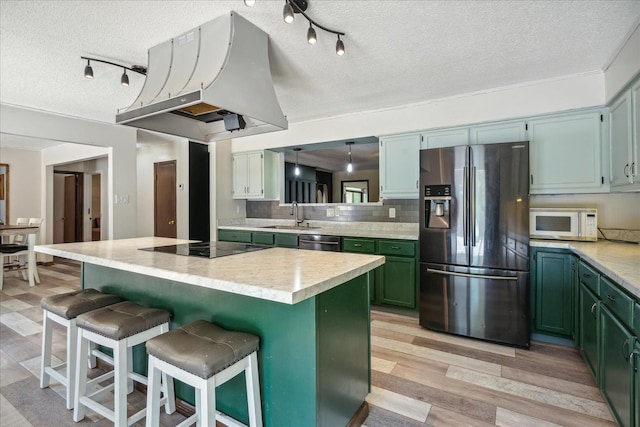 kitchen featuring stainless steel appliances, light hardwood / wood-style floors, a kitchen bar, decorative backsplash, and a textured ceiling