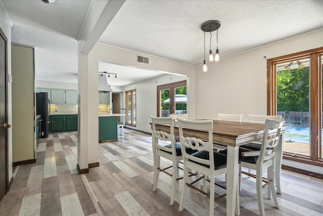 dining area with a textured ceiling, french doors, and light hardwood / wood-style floors