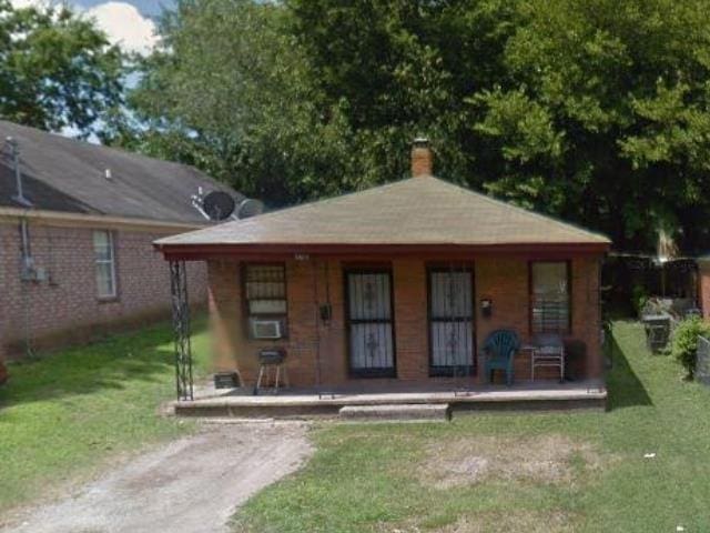 bungalow-style home featuring a chimney, covered porch, and a front yard