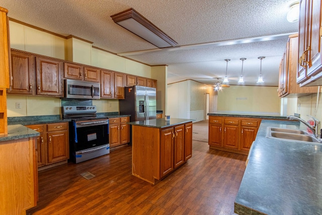 kitchen with appliances with stainless steel finishes, sink, dark hardwood / wood-style floors, a kitchen island, and a textured ceiling